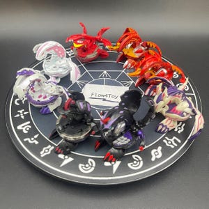 May include: A collection of seven Bakugan transformation toys in red, white, black, and purple, arranged on a circular black mat with white geometric symbols and the text Flow4Toy. The figures feature various mechanical limbs, wings, and spikes.