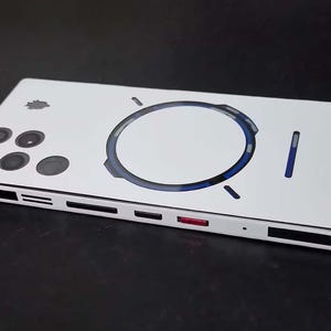 May include: A white smartphone with a rectangular body featuring a circular blue graphic on the back, a cluster of four circular camera lenses, and a side frame with black accents and a single red button. The device has a sleek, flat design.