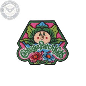 May include: An embroidered patch featuring a Cabbage Patch Kids logo with a central character face surrounded by green leaves, pink background, and two flowers at the bottom, one red and one blue, all enclosed within a black stitched border.