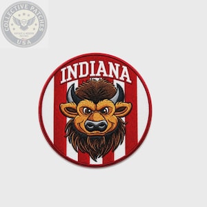 May include: A circular embroidered patch featuring a brown bison head centered over a background of vertical red and white stripes. The word INDIANA is stitched in white capital letters along the top edge of the patch, which has a red border.