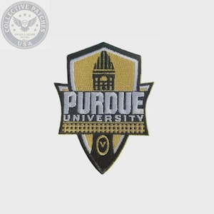 May include: An embroidered patch in the shape of a shield featuring the text PURDUE UNIVERSITY in white lettering. The design includes a black and gold color scheme with a central building icon and a small circle containing the letter V at the bottom.