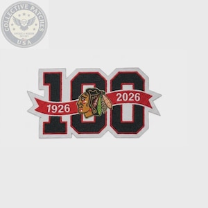 May include: A commemorative embroidered patch featuring the number 100 in black with white and red borders. A red banner overlays the numbers, displaying the years 1926 and 2026. A profile illustration of a person with feathers is centered on the patch.