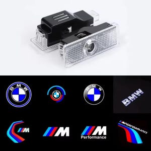 Op de afbeelding: Twee rechthoekige LED-autodeurprojectoren van zwart en doorzichtig plastic. Het onderste gedeelte toont verschillende geprojecteerde BMW-logo's, waaronder het ronde embleem, het M-logo en de tekst BMW en M Performance in blauw, rood en wit.
