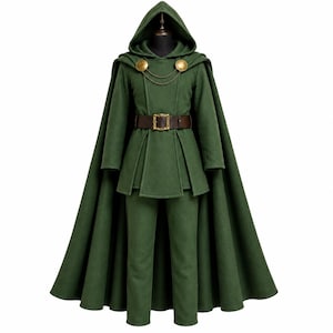 Può includere: Un mantello con cappuccio verde bosco indossato sopra una tunica a maniche lunghe e pantaloni abbinati. Il mantello presenta due chiusure circolari dorate collegate da una catenella. Una cintura in pelle marrone scuro con fibbia dorata stringe la vita.
