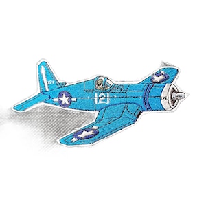 Puede incluir: Un parche bordado con forma de avión de combate azul claro. La aeronave presenta un emblema de estrella blanca sobre un fondo circular azul oscuro en el ala y la cola, con el número 12 impreso en blanco en el lateral del fuselaje.