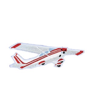 May include: An embroidered patch shaped like a small airplane. The aircraft is white with red stripes along the fuselage and wings, featuring a high-wing design, a tail section with red accents, and landing gear visible beneath the main body.