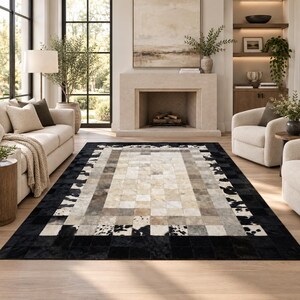 Peut inclure: Un tapis rectangulaire composé de pièces de peau de vache cousues selon un motif géométrique. Le design présente un champ central de carrés crème et beige, entouré d'une bordure de segments de peau gris et tachetés noir et blanc.