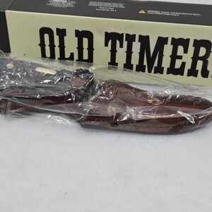 May include: A new Old Timer knife in a brown leather sheath, packaged in a black and tan box. The box has the words "OLD TIMER" in large, bold letters.