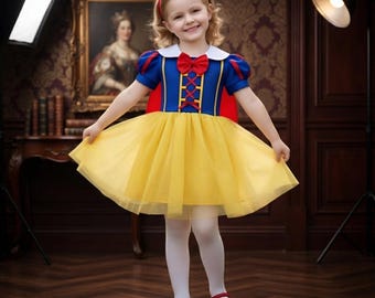 May include: A dress featuring a blue bodice with a red lace-up detail, a white collar, and short puff sleeves. The skirt is made of yellow tulle. The outfit includes a red bow headband and red shoes, creating a classic fairy tale character look.