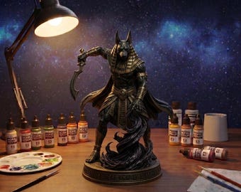 Puede incluir: Una figura detallada de la deidad egipcia Anubis, representada con cabeza de chacal y físico musculoso, sosteniendo una hoja curva. La estatua tiene un acabado en tonos oscuros con detalles dorados y se asienta sobre una base circular.
