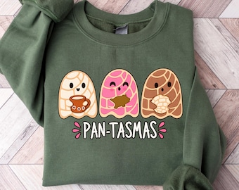 May include: An olive green crewneck sweatshirt featuring a graphic of three ghost-like figures resembling concha sweet bread in white, pink, and brown. The ghosts hold a mug, a cookie, and a piece of bread. The text PAN-TASMAS is printed below.