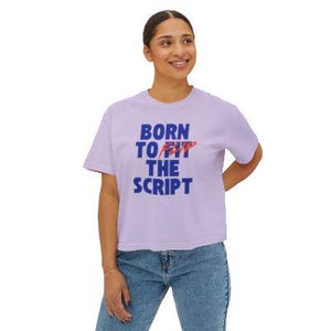 May include: A light purple short-sleeve t-shirt featuring the blue text BORN TO FLIP THE SCRIPT, with the word FLIP written in a stylized red font. The shirt has a crew neckline and a relaxed fit, providing a casual look for everyday wear.