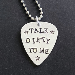 May include: Silver guitar pick necklace with the text "TALK DIRTY TO ME" and stars.
