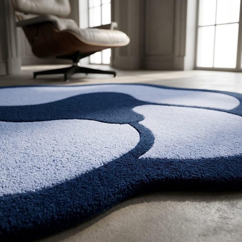 May include: A plush area rug featuring a large-scale, abstract organic pattern in deep navy blue and light periwinkle blue. The rug has a thick, tufted texture with curved, flowing shapes that create a bold, high-contrast visual effect on the floor.
