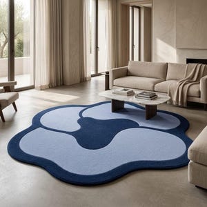 May include: A large, floor-based area rug with an organic, cloud-like shape. The rug features a deep navy blue border and central accent, contrasting with lighter periwinkle blue sections that fill the remaining curved, petal-like segments.