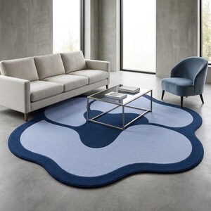 May include: A large, irregularly shaped area rug featuring a layered, organic floral design. The rug is composed of deep navy blue and light periwinkle blue sections with soft, rounded edges, creating a distinct, flowing pattern on the floor.
