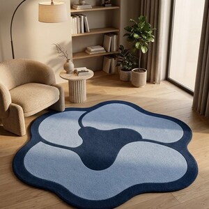 May include: A large, flower-shaped area rug featuring a deep navy blue center surrounded by four light blue, rounded petals. The rug has a thick, dark navy blue border that follows the organic, wavy outline of the floral design.