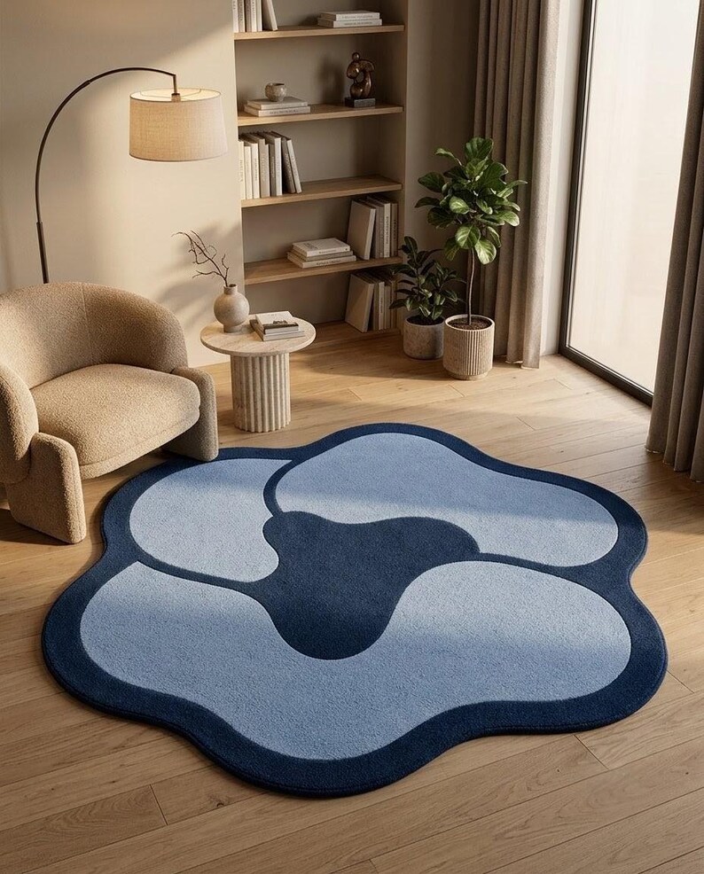 May include: A large, flower-shaped area rug featuring a deep navy blue center surrounded by four light blue, rounded petals. The rug has a thick, dark navy blue border that follows the organic, wavy outline of the floral design.