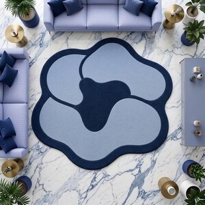 May include: An irregular, flower-shaped area rug featuring a deep navy blue border and central core, contrasted with light blue, rounded petal-like sections. The rug has a soft, textured surface and a distinct, organic, non-symmetrical silhouette.