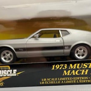 May include: A white ceramic mug with a black handle and the text "But First, Coffee" in a black, bold font. The mug is on a white surface.