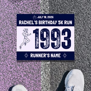 Op de afbeelding: Een rechthoekig startnummer met een donkerblauwe boven- en onderrand en een wit midden. Het bevat de tekst JULY 18, 2026, RACHEL'S BIRTHDAY 5K RUN, 1993 en RUNNER'S NAME, samen met een taartpictogram, sterpictogrammen en een lijntekening van een loper.