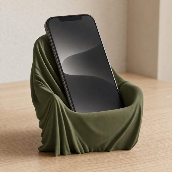 Close-up desk view of the DrapeDock smartphone holder in Dark Green with a blank-screen phone