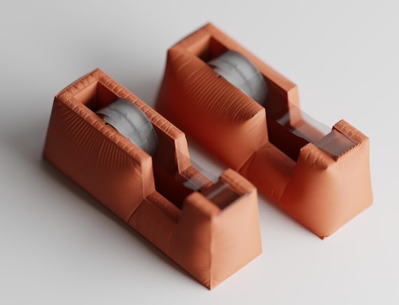 High-angle close-up of two complete Clothcrest Tape Dispenser tape dispenser silhouettes in Terracotta