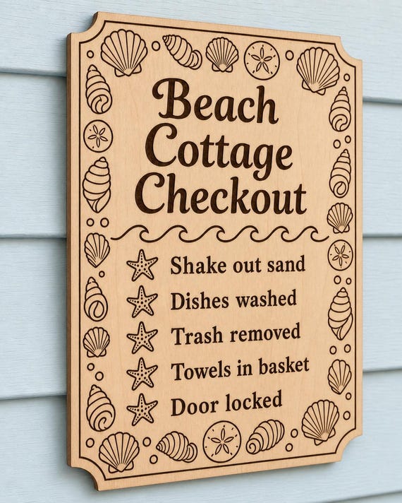 ShoreStay engraved birch beach cottage checkout sign mounted on a pale-blue wall from a close side angle.