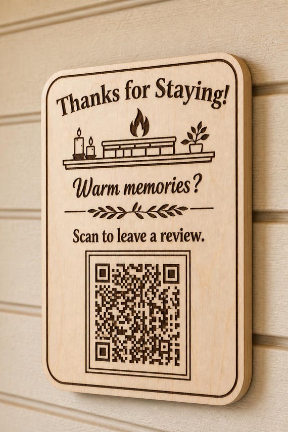 Fireside Keepsake engraved birch review sign mounted on a warm cream wall from a close side angle with a finished sample QR code.