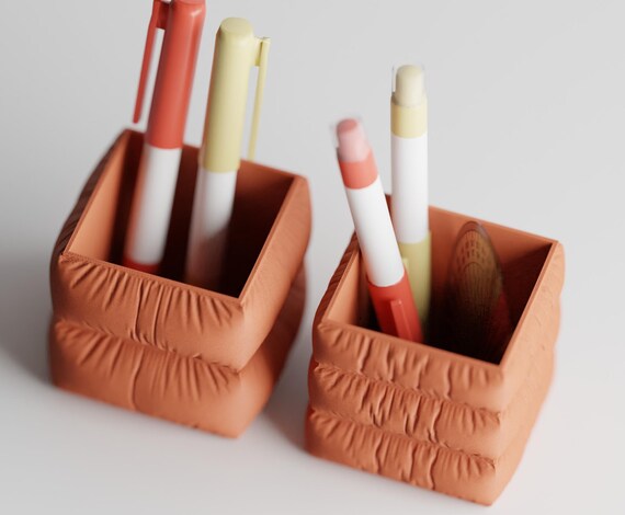 High-angle close-up of both Puffridge Pen Cup pen holder silhouettes in Terracotta