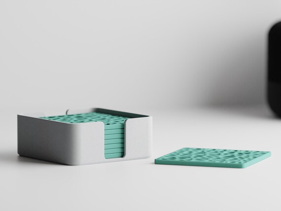 Low-angle close-up of eight Fernwork Coaster Set square coasters stacked in the storage holder