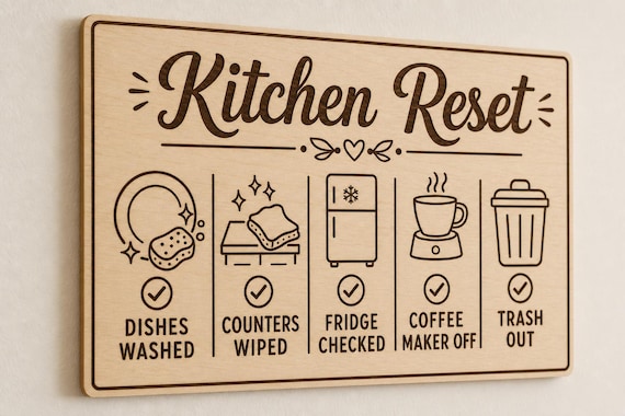 BrightNest engraved birch kitchen reset checklist mounted on a warm-white wall from a close side angle.