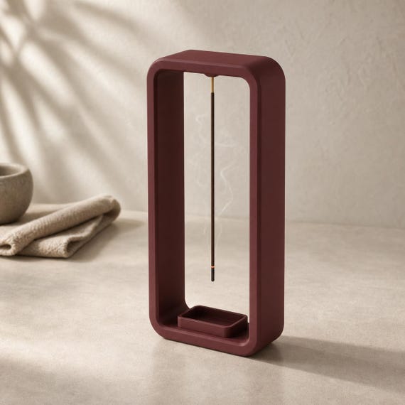 Close-up of a Maroon Red EmberLift Incense Stand in a calm meditation space