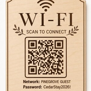 May include: A rectangular light-colored wooden sign with dark brown engraved text and a QR code. The sign features a Wi-Fi symbol, the text WI-FI SCAN TO CONNECT, the network name PINEGROVE GUEST, the password CedarStay2026!, and Enjoy Your Stay.
