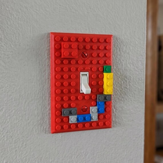 Close-up of a red BuildBoard 1-Gang toggle wall plate installed with colorful blocks attached