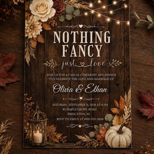 May include: A rectangular wedding invitation card on a dark wood background featuring the text NOTHING FANCY just love, Olivia & Ethan, and event details. Decorated with string lights, a lantern, a white pumpkin, and autumn floral accents.