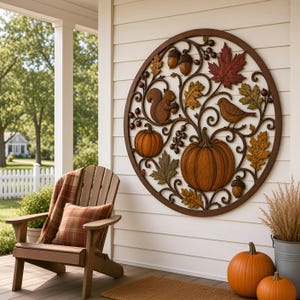 May include: A circular metal wall art piece featuring an intricate design of autumn elements including pumpkins, a squirrel, a bird, acorns, and maple leaves in shades of brown, orange, and green, mounted on a white horizontal paneled wall.