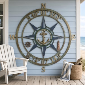 May include: A large circular metal compass rose wall art piece featuring a central anchor, a small ship wheel, and a lighthouse. The outer ring displays the cardinal directions N, S, E, W and the coordinates N 40° 01' 59.9" and W 74° 07' 14.8".