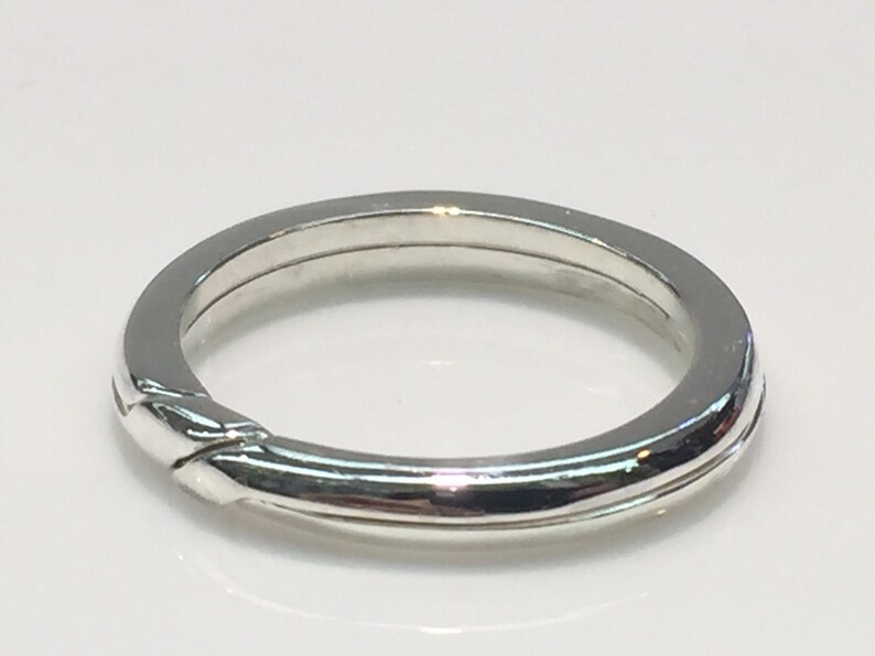 May include: A silver ring with a unique interlocking design. The ring is smooth and polished.