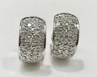 Puede incluir: Un par de pendientes de aro de plata con una fila de pequeños diamantes transparentes alrededor de todo el aro.