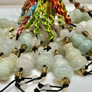 Op de afbeelding: Een verzameling jade-kalebas-charms met zwarte koorden en witte kralen. De kalebassen zijn een symbool van geluk en voorspoed in de Chinese cultuur.