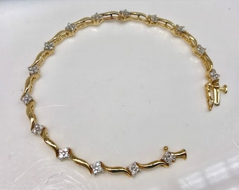 May include: A gold bracelet with a wavy design and small diamond accents.