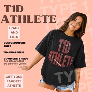 May include: A black short-sleeved t-shirt featuring the text T1D ATHLETE in a maroon, distressed, circular graphic design. The shirt has a crew neckline and a relaxed fit, with the text printed in a bold, sans-serif font across the chest area.