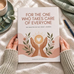 May include: A white journal titled FOR THE ONE WHO TAKES CARE OF EVERYONE AN UNDATED 90-DAY RESET JOURNAL. The cover features an illustration of two hands holding a glowing sun with a heart in the centre, surrounded by green leaves and pink hills.