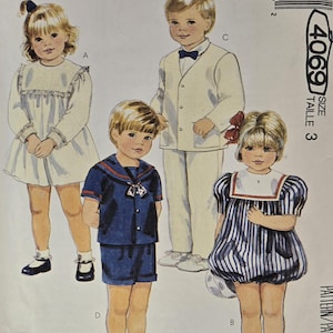 May include: Vintage McCall's sewing pattern featuring illustrations of children's clothing. The designs include a white dress, a sailor suit, a cream-colored suit with a bow tie, and a blue and white striped dress. The pattern is size 3.