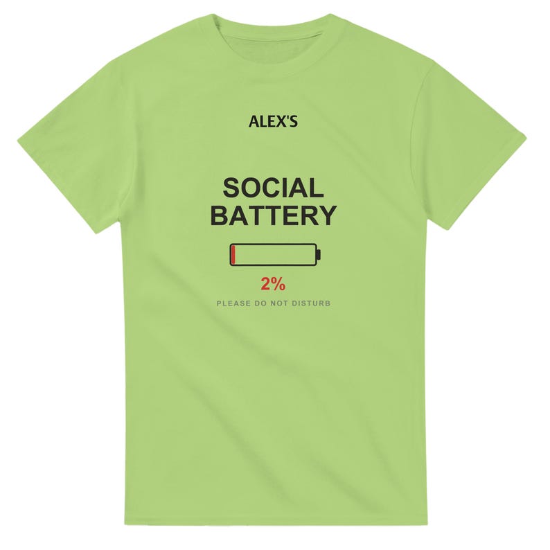 以下が含まれることがあります： 明るいライムグリーンの半袖Tシャツ。前面中央に黒字で「ALEX'S SOCIAL BATTERY」と書かれ、その下に赤色で2%と表示されたバッテリーアイコンと、小さなグレーの文字で「PLEASE DO NOT DISTURB」とプリントされています。