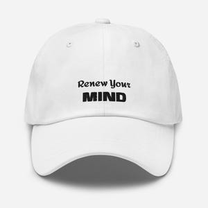Puede incluir: Una gorra de béisbol blanca con el texto negro bordado Renew Your Mind en el panel frontal. La gorra tiene una corona estructurada, una visera curva y un botón en la parte superior. El diseño está centrado en la parte delantera de la gorra.