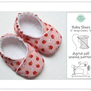 Può includere: Un paio di scarpine per bambini con stampa di mele rosa. Le scarpe hanno un interno bianco e un bordo a balze. L'immagine include anche una grafica che dice "Baby Shoes Wrap-Overs" e "digital pdf sewing pattern".