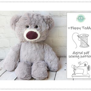 May include: A plush, gray teddy bear with a dark burgundy nose and mouth. The bear is sitting on a light-colored wooden surface. A digital PDF sewing pattern is displayed on a white card, with the text "Floppy Teddy".