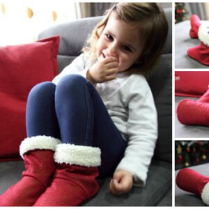 May include: Red glittery boots with white faux fur trim. The boots are worn by a person wearing blue leggings. A red pillow is in the background. The boots appear to be for children.